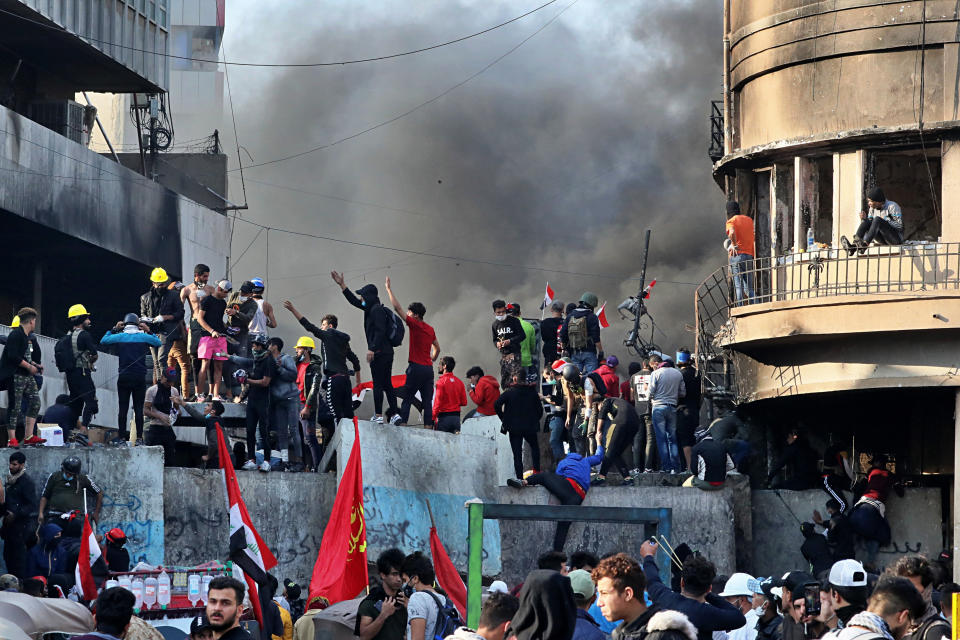 Anti-government protesters stand on a concrete wall erected by security forces to close Rasheed Street during clashes in Baghdad, Iraq, Thursday, Nov. 28, 2019. Scores of protesters have been shot dead in the last 24 hours, amid spiraling violence in Baghdad and southern Iraq, officials said. (AP Photo/Khalid Mohammed)