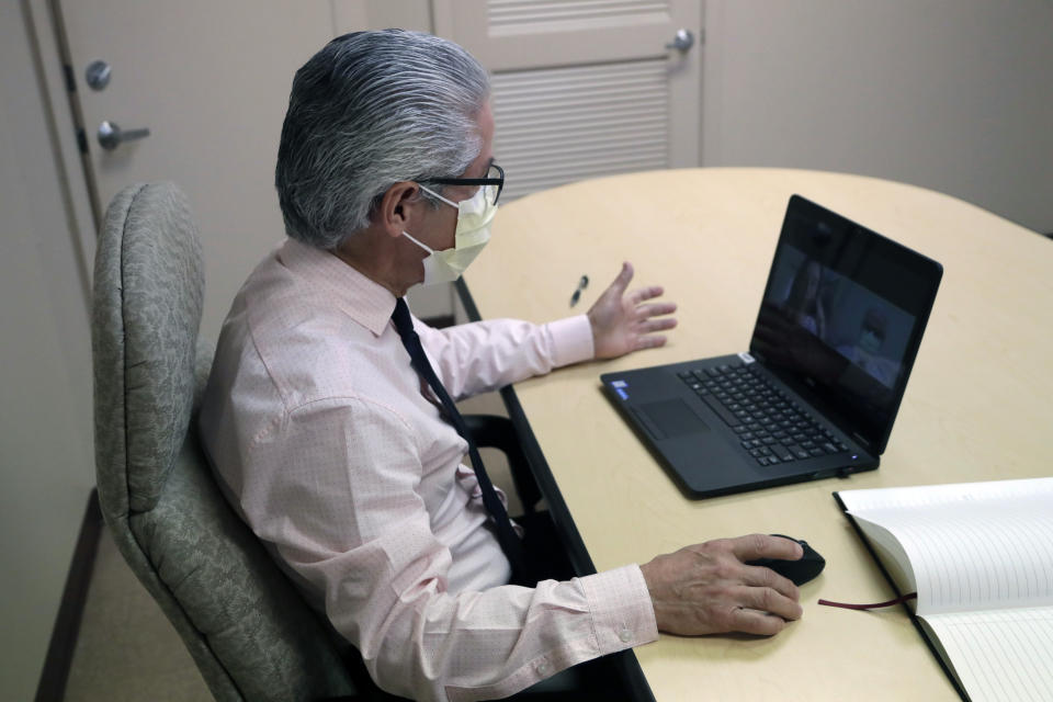 In this Wednesday, May 13, 2020 photo, Dr. Alvaro Mejia Echeverry does a virtual interview on the subject of contact tracing at the Florida Dept. of Health in Miami-Dade County, during the new coronavirus pandemic, in Doral, Fla. In state after state, the local health departments charged with doing the detective work of running down the contacts of coronavirus patients are falling well short of the number of people needed to do the job. (AP Photo/Lynne Sladky)