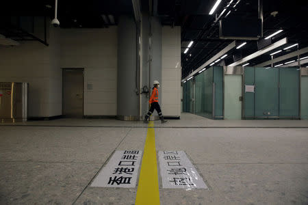 FILE PHOTO: A worker walks past a line dividing Hong Kong (L) and mainland Chinese control zone as part of the joint immigration checkpoint inside West Kowloon Terminus for the Guangzhou-Shenzhen-Hong Kong Express Rail Link in Hong Kong, China March 23, 2018. Lama Leung/Hong Kong Economic Times Pool via Reuters/File Photo