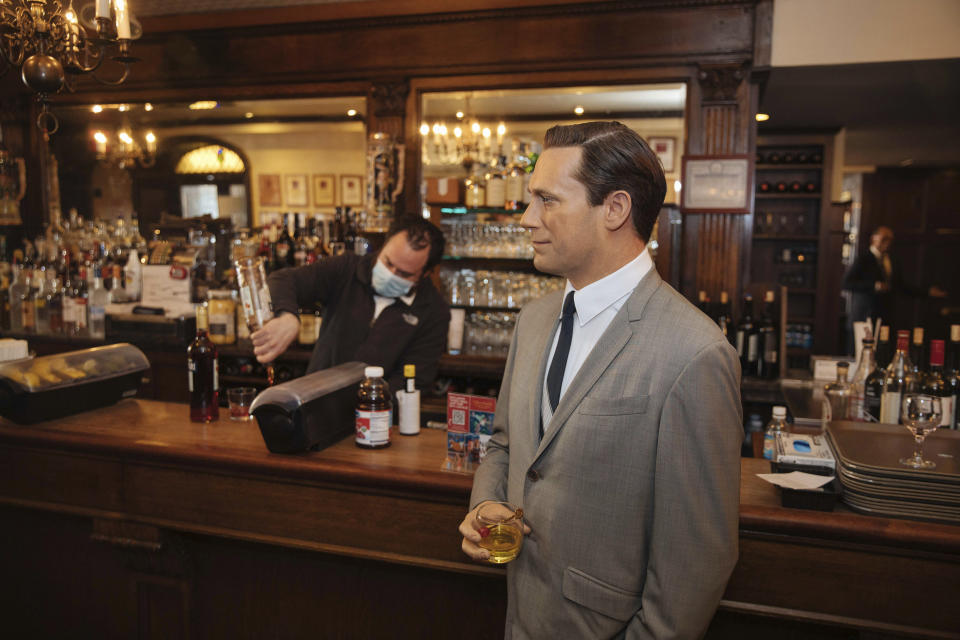 A wax statue of actor John Hamm stands by the bar with a drink at Peter Luger Steakhouse on Friday, Feb, 26, 2021, in New York. The statue, on loan from Madame Tussauds, will help fill out the restaurant during COVID-19 occupancy restrictions. (AP Photo/Kevin Hagen)
