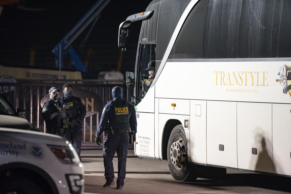 Department of Homeland Security officers talk to the driver of a bus carrying migrant children and teenagers from the southern border of the United States as it waits to enter the site of a temporary holding facility that opened on Sunday, March 14, 2021 south of Midland, Texas. (Eli Hartman/Odessa American via AP)