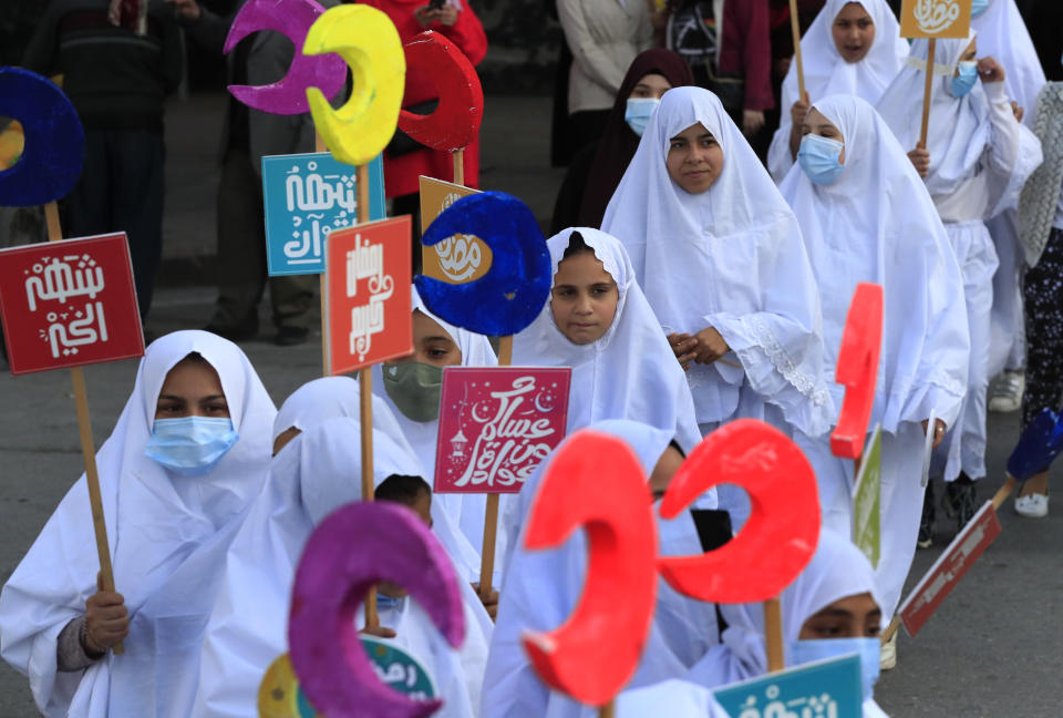 Lebanese girls hold crescents during street performances celebrating the upcoming Muslim holy month of Ramadan, in the southern port city of Sidon, Lebanon, Thursday, March 31, 2022. (AP Photo/Mohammed Zaatari)