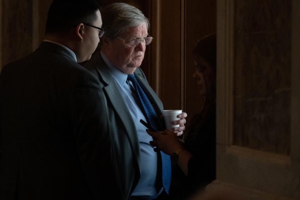 Rep. Vic Miller, D-Topeka, peers out from a window in the House chambers while speaking with an aide Monday afternoon.