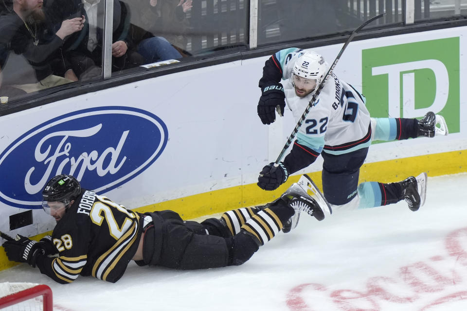 Boston Bruins defenseman Derek Forbort (28) and Seattle Kraken right wing Oliver Bjorkstrand (22) hit the ice after colliding in the third period of an NHL hockey game, Thursday, Feb. 15, 2024, in Boston. (AP Photo/Steven Senne)