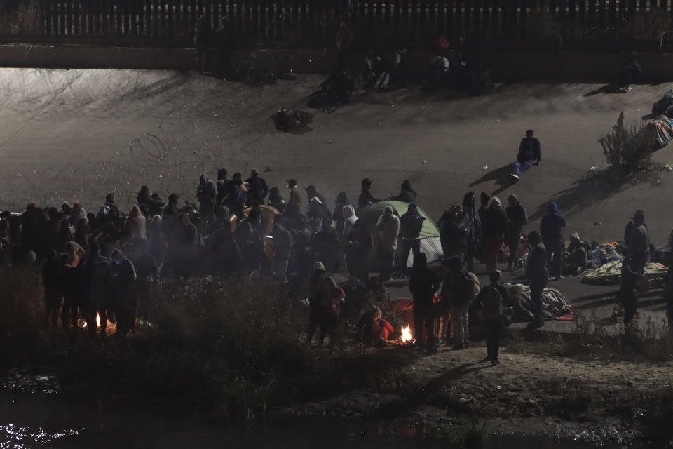 Migrantes reunidos en torno a una hoguera cerca de la frontera entre México y Estados Unidos, desde Ciudad Juárez, México, el martes 20 de diciembre de 2022. La Corte Suprema de Estados unidos emitió una orden temporal para mantener las restricciones de la pandemia sobre las solicitudes de asilo, aunque podría ser breve. (AP Foto/Christian Chavez)