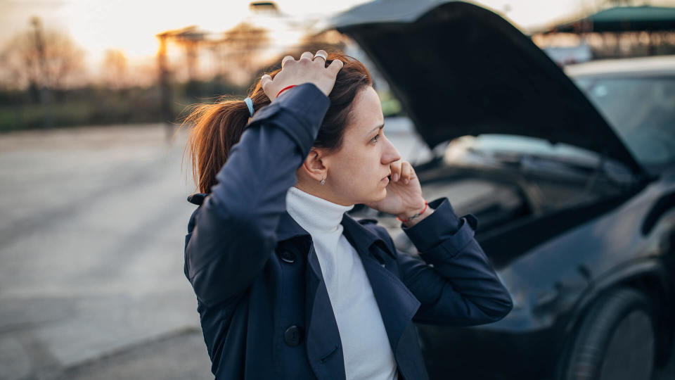 Young, stressed woman is calling emergency service  to help her with a broken car.