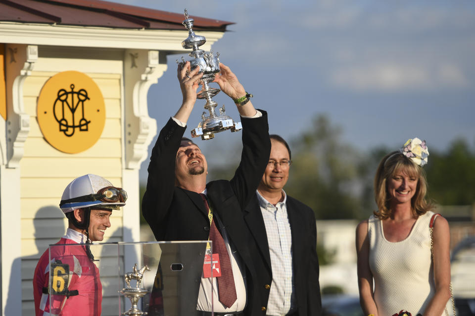 Rombauer trainer Michael McCarthy, second from left, holds the trophy as jockey Flavien Prat, left, and horse owners John Fradkin and Diane Fradkin look on after winning the 145th Preakness Stakes horse race at Pimlico Race Course, Saturday, May 15, 2021, in Baltimore. (AP Photo/Will Newton)