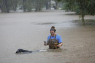 Adelle Puma and her dog "Ridge" makes their way from the submerged Mary Xing bridge over Marys Creek that leads into Clear Creek as Tropical Storm Beta rainfall trained over the area Tuesday, Sept. 22, 2020, in Friendswood, Texas. Puma and her husband just moved from Breaex Bridge, La., a moth ago and their home sits next to the bridge. (Steve Gonzales/Houston Chronicle via AP)