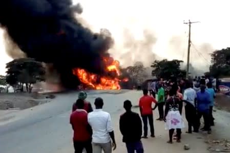 People look towards a fire following a fuel truck collision in Rubirizi