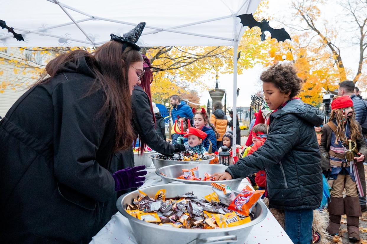 A child grabs candy out of a bowl on the grounds of Rideau Hall in Ottawa on Tuesday. (Spencer Colby/The Canadian Press - image credit)