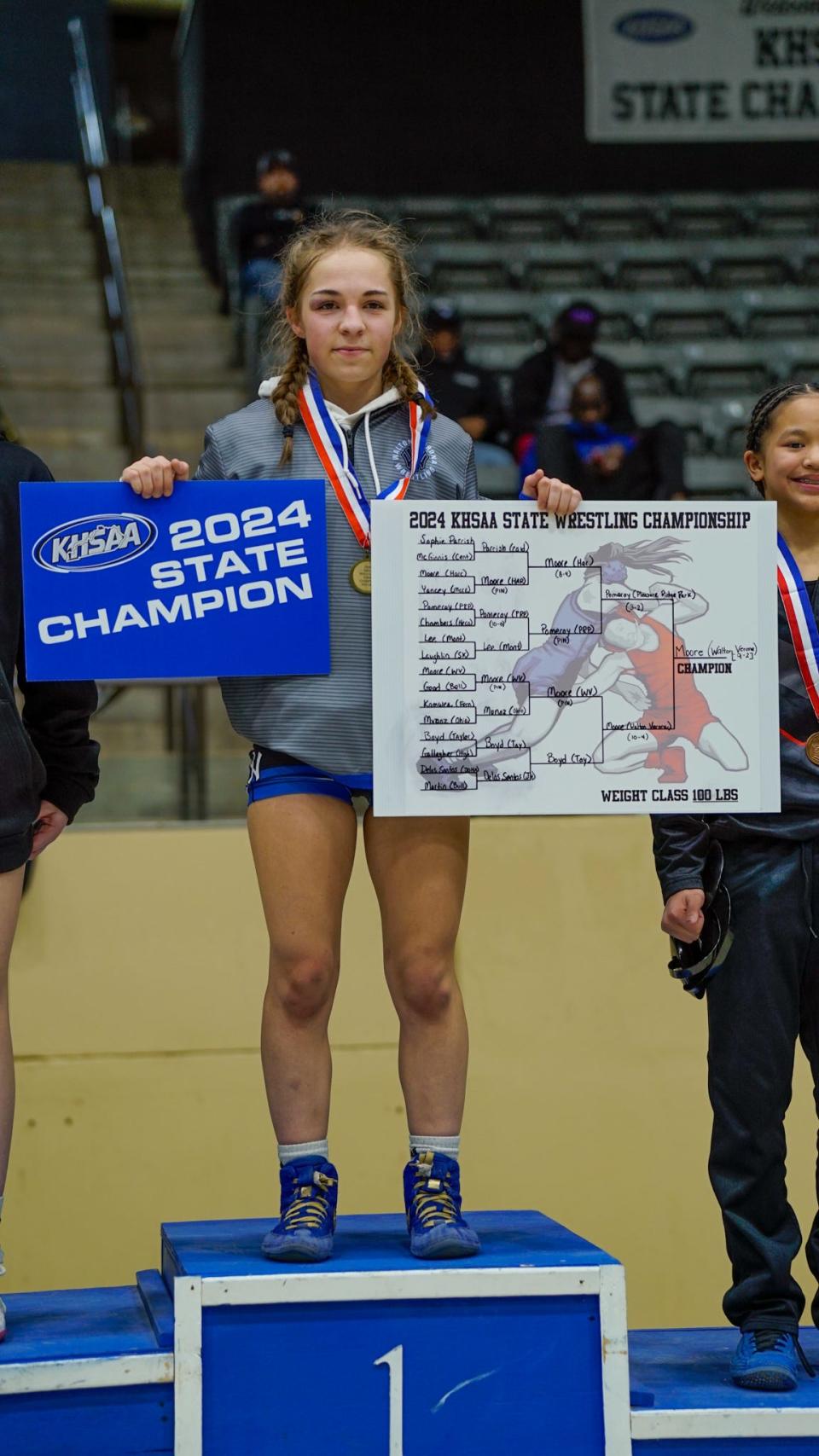 Walton-Verona's Emma Moore poses with her state champion posters after she won the 100-pound state title at the KHSAA girls wrestling state tournament on Feb. 17, 2024, at Alltech Arena in Lexington, Kentucky.