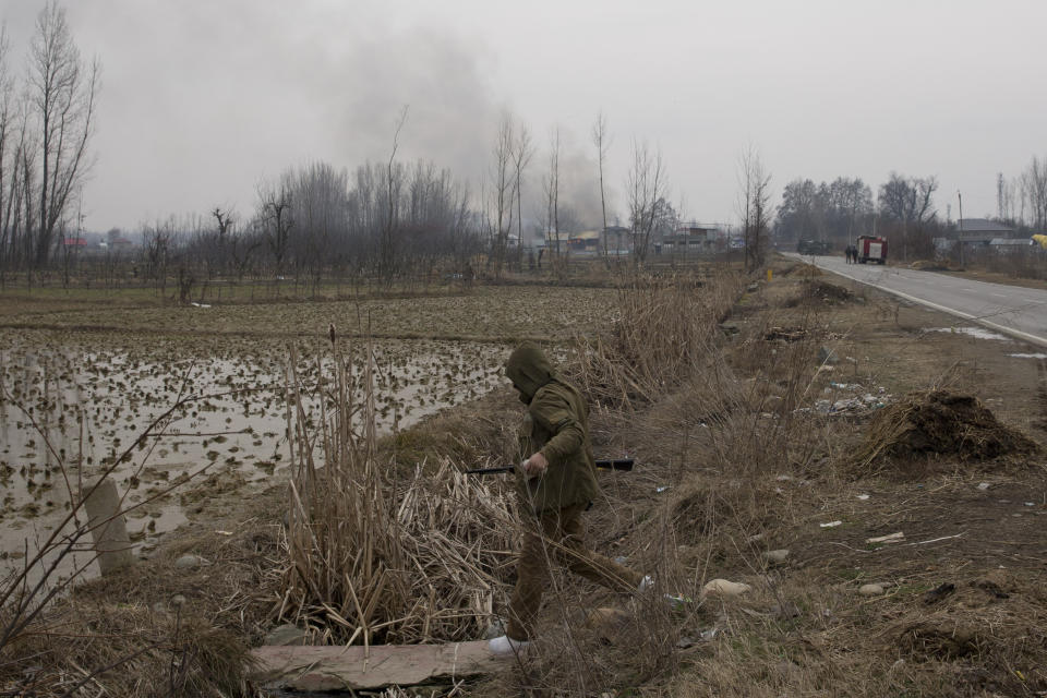 An Indian police man rushes to chase Kashmiri protesters near the the site of a gun battle in Pulwama, south of Srinagar, Indian controlled Kashmir, Monday, Feb. 18, 2019. Tensions continued to rise in the aftermath of a suicide attack in disputed Kashmir, with seven people killed Monday in a gunbattle that broke out as Indian soldiers scoured the area for militants. (AP Photo/ Dar Yasin)