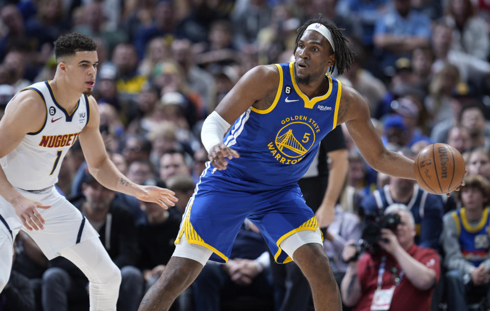 Golden State Warriors forward Kevon Looney, right, looks to pass the ball as Denver Nuggets forward Michael Porter Jr. defends in the first half of an NBA basketball game Sunday, April 2, 2023, in Denver. (AP Photo/David Zalubowski)