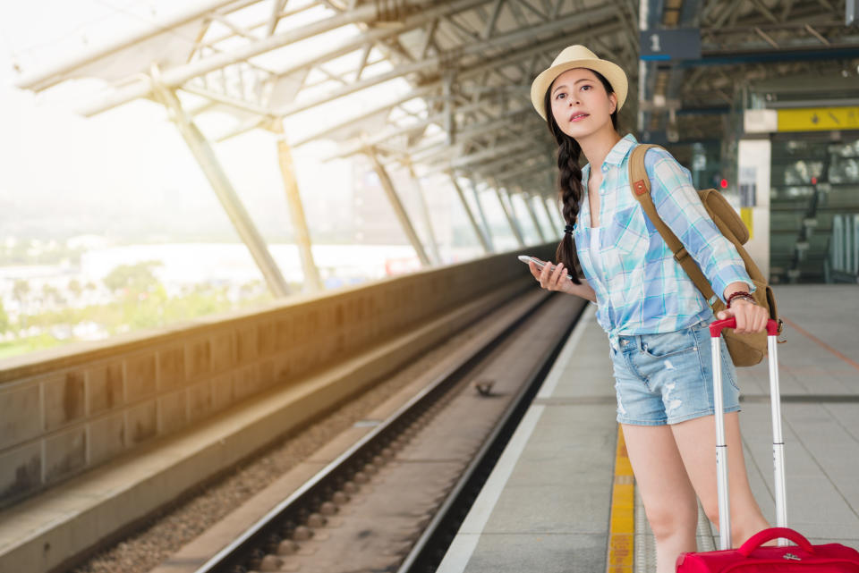 beautiful young woman looking at the railroad for delay late train coming. Asian holiday travel concept.