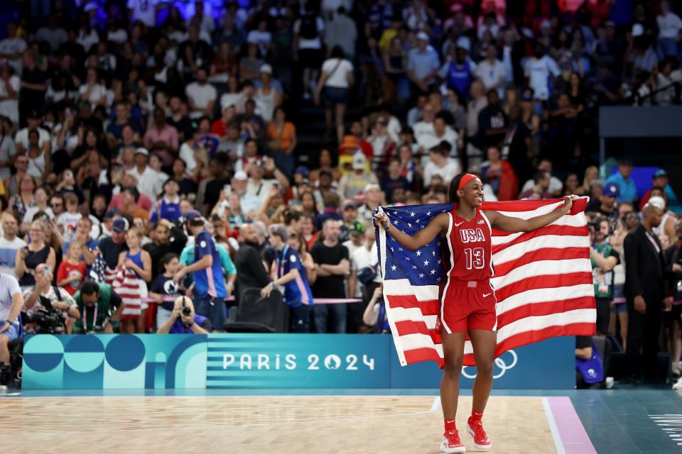 PARIS, FRANCE - AUGUST 11: Jackie Young #13 of Team United States celebrates with the American flag after her team's victory against Team France during the Women's Gold Medal game between Team France and Team United States on day sixteen of the Olympic Games Paris 2024 at Bercy Arena on August 11, 2024 in Paris, France. (Photo by Matthew Stockman/Getty Images) ORG XMIT: 776138675 ORIG FILE ID: 2166336982