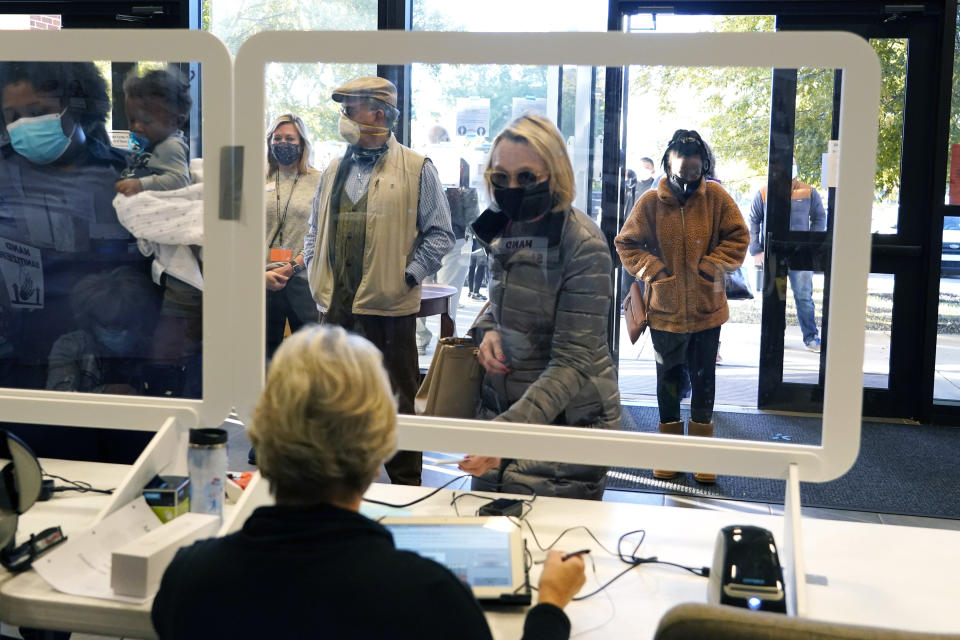 FILE - In this Tuesday, Nov. 3, 2020, file photo, a masked election worker sits behind a clear barrier as she performs identification checks of potential voters on Election Day in Ridgeland, Miss. As Republican state lawmakers across the country push new restrictions on voting, a key element focuses on cleaning voter rolls to ensure only those who are eligible are registered to vote. There is bipartisan consensus that up-to-date and accurate voter rolls are important to ensuring election integrity and limiting fraud, but there is little agreement on the best way to accomplish it. (AP Photo/Rogelio V. Solis, File)