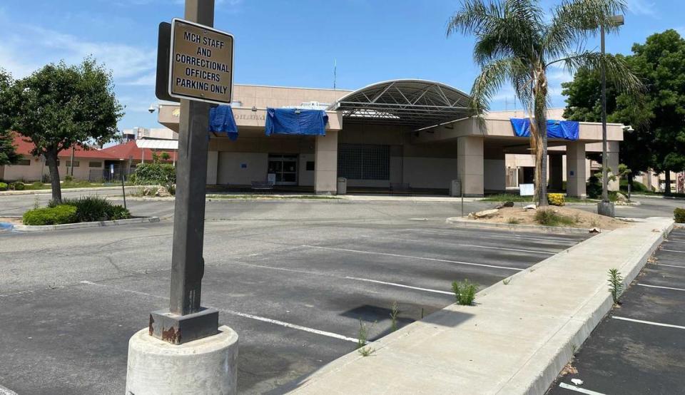 An empty parking lot with cracked pavement, faded stripes and weeds popping up are evident at the closed Madera Community Hospital, with blue tarps covering where the facility’s name was formerly displayed, on Tuesday, May 16, 2023. The hospital closed in January.