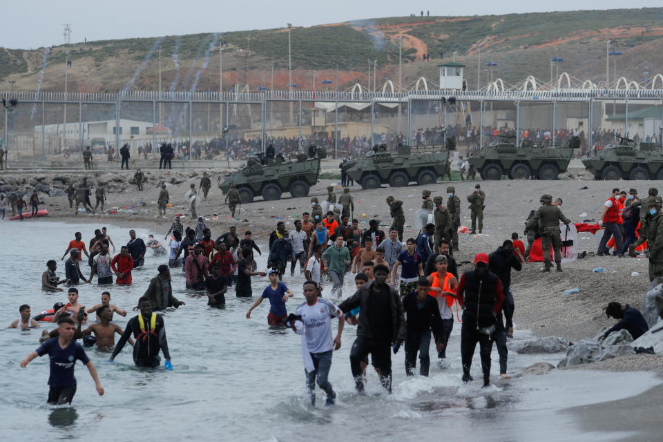 Moroccan citizens walk in the water as Spanish legionnaires patrol the area near the fence on a beach in El Tarajal. (Reuters)