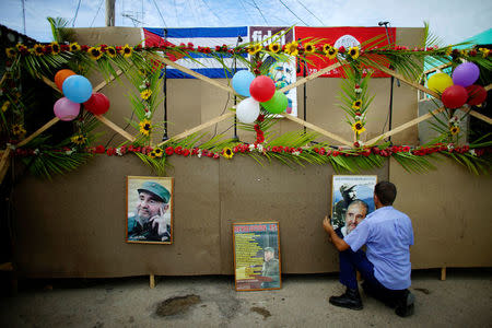 A man hangs pictures of late Cuban president Fidel Castro on a stage to be used during celebrations of what would have been his 91st birthday in San Antonio de los Banos, Cuba, August 10, 2017. Picture taken on August 10, 2017. REUTERS/Alexandre Meneghini