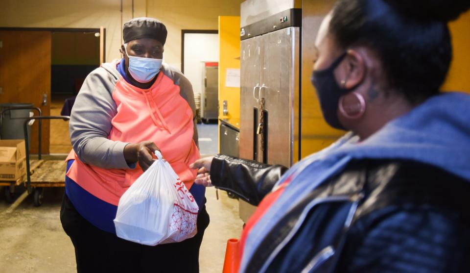 Riddle Elementary School cafeteria worker Cynthia Trainor passes out to-go meals to a parent for her stay-at-home remote-learning student Wednesday afternoon, Jan. 5, 2022, outside Riddle's cafeteria. Schools in the district are currently conducting classes online due to COVID-19 through at least the end of the week.