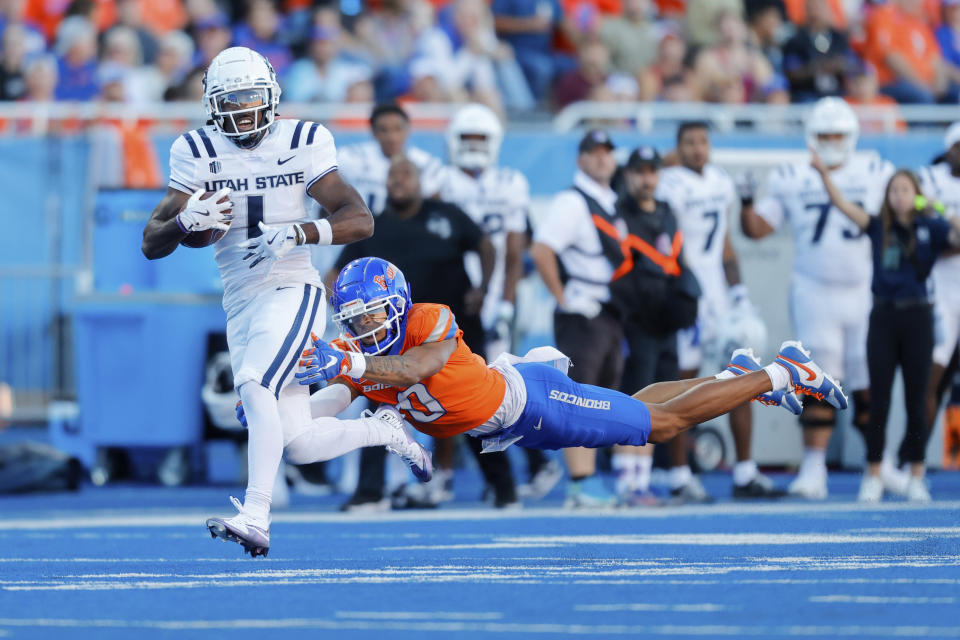 Utah State wide receiver Jalen Royals (1) runs through a diving tackle attempt by Boise State safety Ty Benefield (0) for a 59-yard touchdown reception in the first half of an NCAA college football game, Saturday, Oct. 5, 2024, in Boise, Idaho. . (AP Photo/Steve Conner)