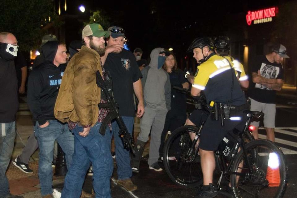 Joshua Cody Case stands with an AR-15 rifle near an Asheville Police bicycle officer at a June 21, 2020, demonstration in downtown Asheville. Carrying of dangerous weapons at a demonstration is illegal in North Carolina.