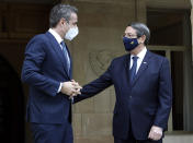 This image provided by Cyprus' press and information office shows Cyprus President Nicos Anastasiades, right, gestures with Greece's Prime minister Kyriakos Mitsotakis, prior to their meeting at the presidential palace in capital Nicosia, Cyprus, Monday, Feb. 8, 2021. Mitsotakis is in Cyprus on a one day official visit. (Stavros Ioannides, PIO via AP)