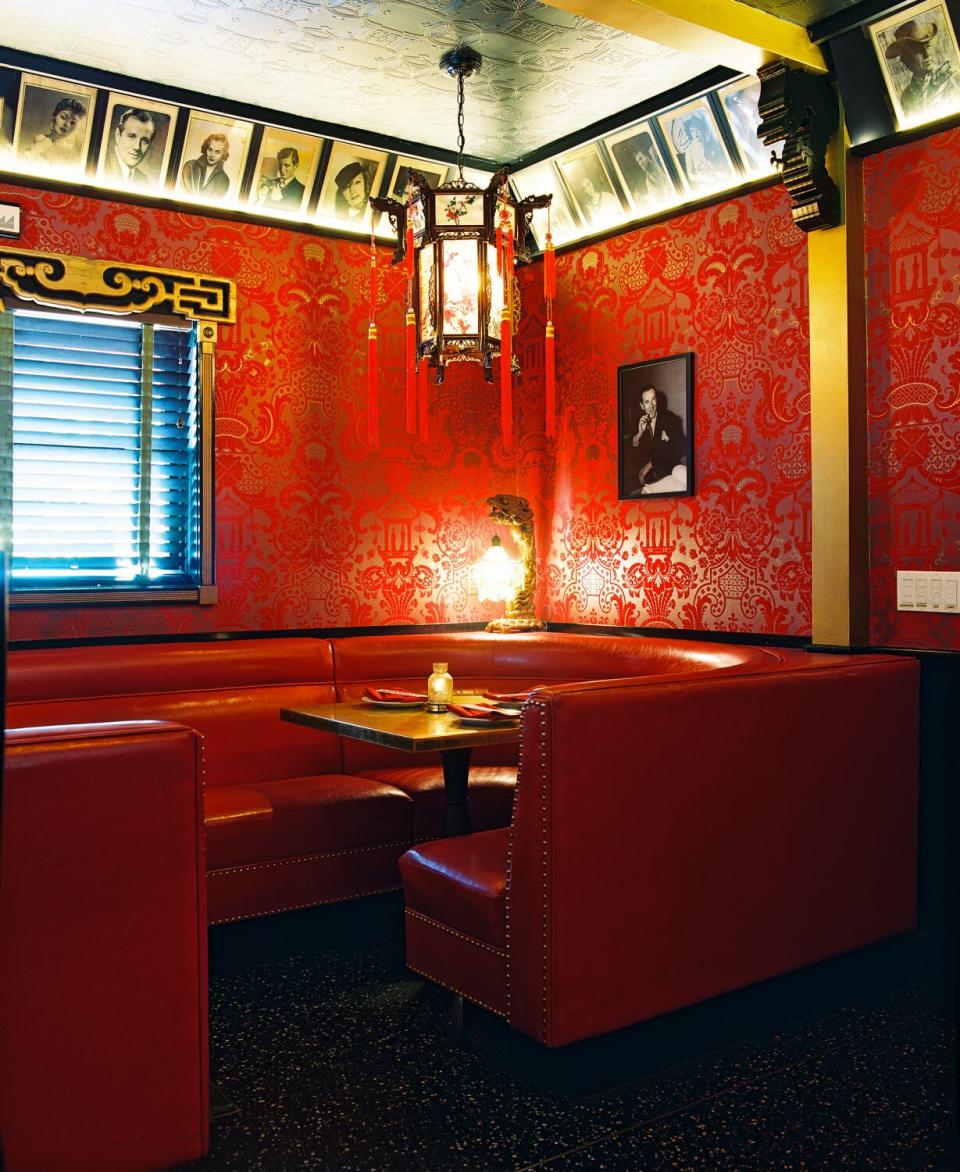 A photo of red booths nestled in a corner of a restaurant with red walls.