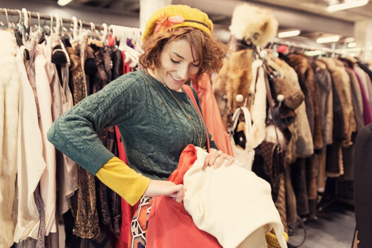 Young woman shopping in thrift market of vintage clothes.