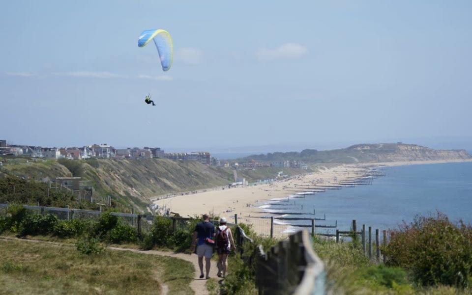 Further along the coast at Boscombe beach, a paraglider takes to the skies above the cliffs (Andrew Matthews/PA) (PA Wire)