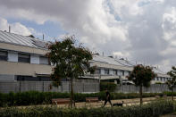 A man walks with his dog in front of houses with solar panels in Rivas Vaciamadrid, Spain, Thursday, Sept. 15, 2022. The energy crisis is accelerating the installation of solar panels by residential communities in Spain who want to become self-sufficient. Recent legislation has allowed so-called "energy communities" to generate renewable power through collective installations. (AP Photo/Manu Fernandez)