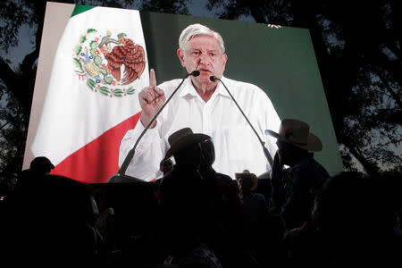 People watch Mexico's President Andres Manuel Lopez Obrador on a video screen during an event in Badiraguato, in the Mexican state of Sinaloa, Mexico February 15, 2019. REUTERS/Daniel Becerril