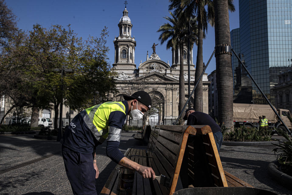 Un trabajador pinta un banco en la Plaza de Armas en el centro de Santiago, Chile, el miércoles 12 de agosto de 2020. (AP Foto/Esteban Felix)