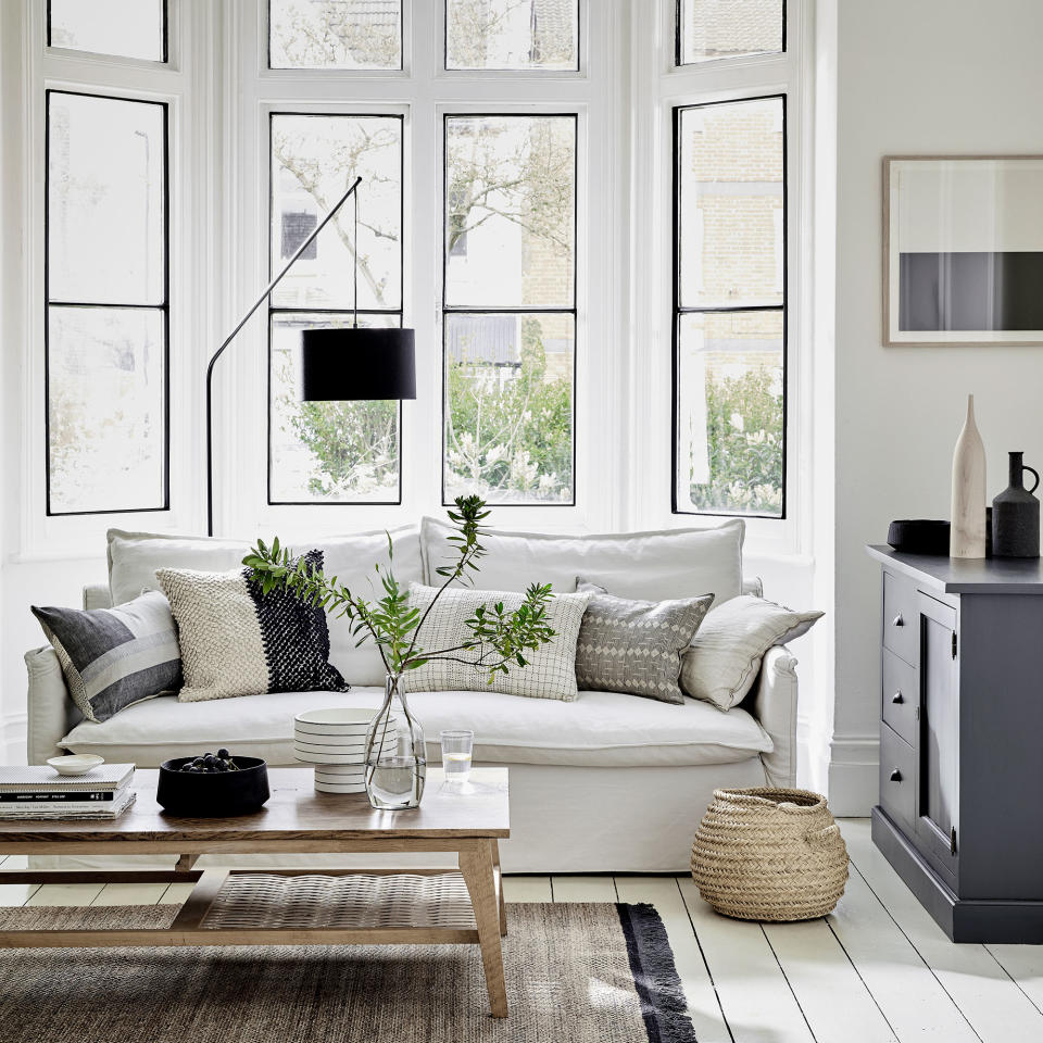 White living room with sofa, bay window and wooden coffee table