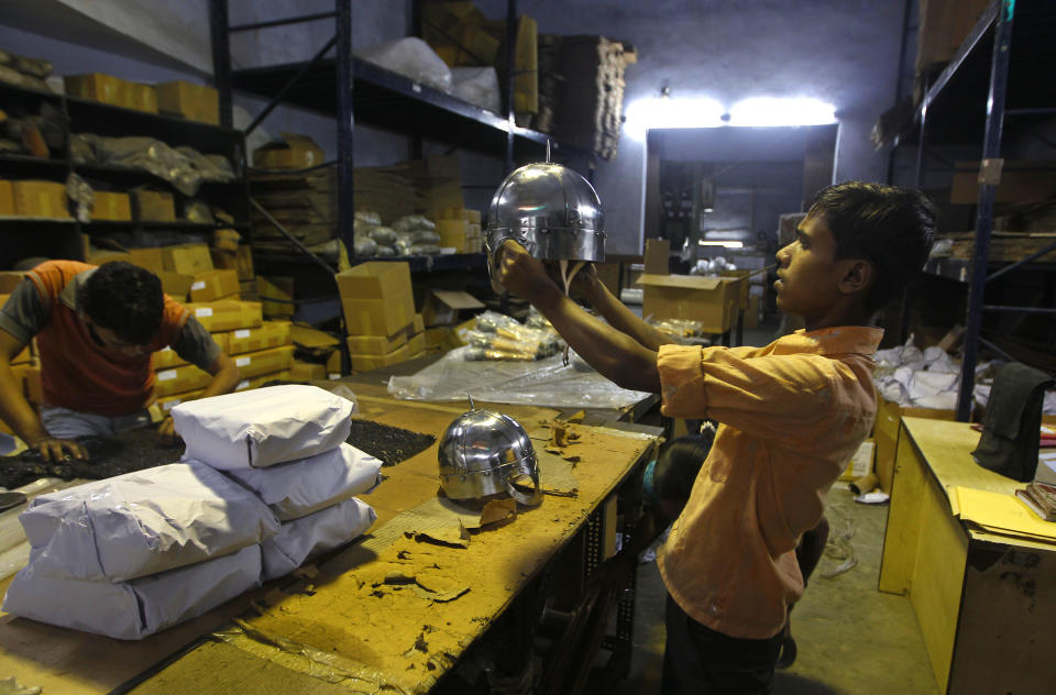 In this, June 2, 2012 photograph, a worker inspects a helmet before packing it for a Hollywood period movie at a workshop owned by Indian businessman Ashok Rai, unseen, in Sahibabad, India. From Hollywood war movies to Japanese Samurai films to battle re-enactments across Europe, Rai is one of the world's go-to men for historic weapons and battle attire. (AP Photo/Saurabh Das)