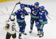 Vegas Golden Knights' Mark Stone (61) skates past as Vancouver Canucks' Alexander Edler (23), Bo Horvat (53) and J.T. Miller (9) celebrate a goal by Horvat during the second period of an NHL Western Conference Stanley Cup playoff game, Sunday, Aug. 30, 2020, in Edmonton, Alberta. (Jason Franson/The Canadian Press via AP)