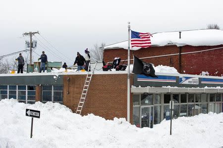 Workers remove snow from the roof of a post office in the City of Lackawanna, New York, November 22, 2014. REUTERS/Aaron Ingrao