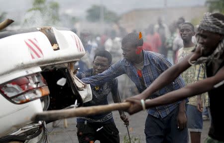 Protesters destroy a car belonging to a policeman after they intercepted him at a barricade during demonstrations against the ruling CNDD-FDD party's decision to allow President Pierre Nkurunziza to run for a third five-year term in office, in Bujumbura, Burundi April 30, 2015. REUTERS/Thomas Mukoya