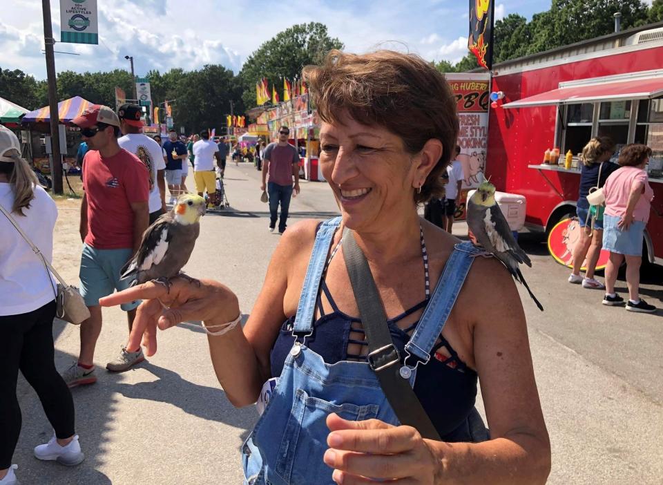 At the 2022 Chesterfield County Fair, Anna Espinoza of Henrico, Va. strikes a pose with her cockatiels Sweetie and Tiki Wiki, on the right.