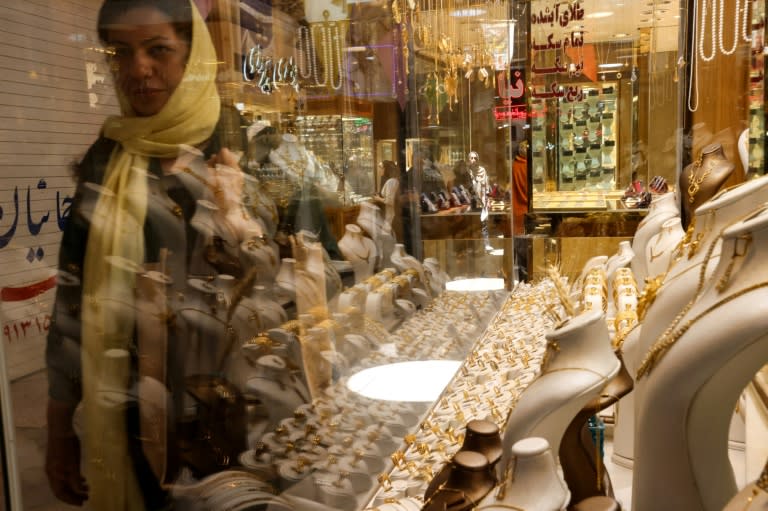 A woman walks past the display window of a gold jewelry shop in the old market of Yazd, in central Iran, on July 3, 2023 (ATTA KENARE)