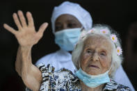 Zelia de Carvalho Morley, 106, waves after receiving a shot of China's Sinovac CoronaVac vaccine for the new coronavirus at the retirement home where she lives in Rio de Janeiro, Brazil, Wednesday, Jan. 20, 2021. De Carvalho Morley lived through the 1918 flu pandemic. (AP Photo/Bruna Prado)