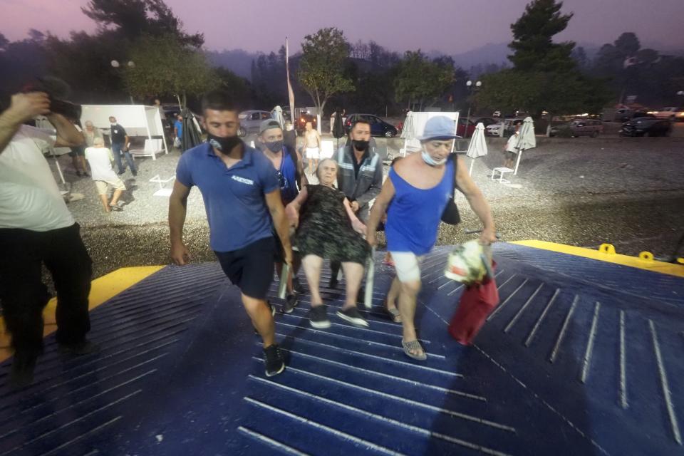 A person is carried in a chair onto a ferry during evacuations in Evia.