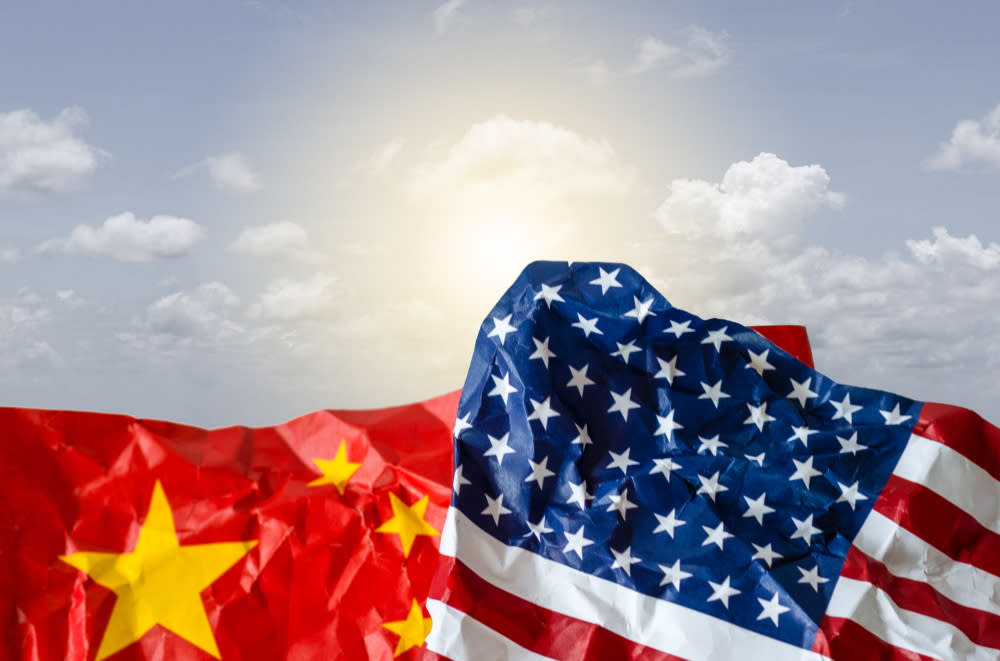  Chinese flag and US flag in front of blue sky. 