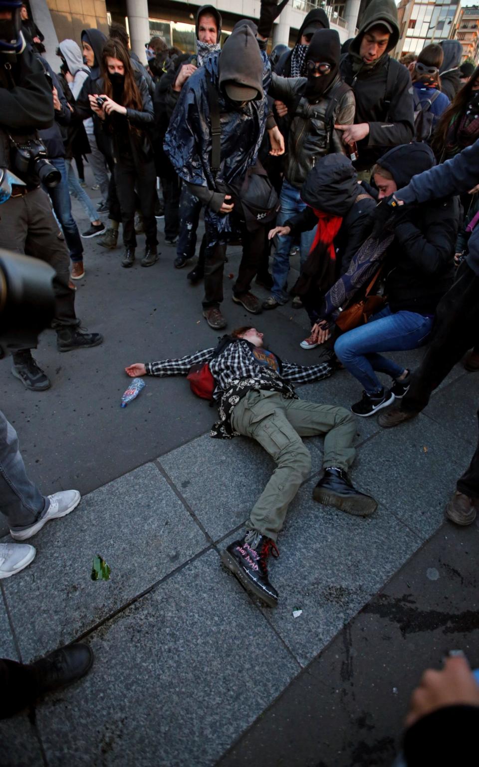 A demonstrator lays on the ground during clashes with police after early results in the first round of 2017 French presidential election, in Paris - Credit:  JEAN-PAUL PELISSIER/REUTERS