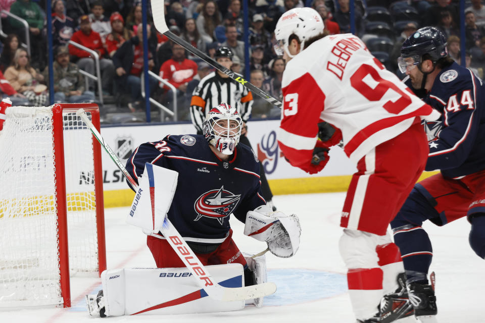 Columbus Blue Jackets' Spencer Martin, left, makes a save against Detroit Red Wings' Alex DeBrincat (93) during the first period of an NHL hockey game Monday, Oct. 16, 2023, in Columbus, Ohio. (AP Photo/Jay LaPrete)