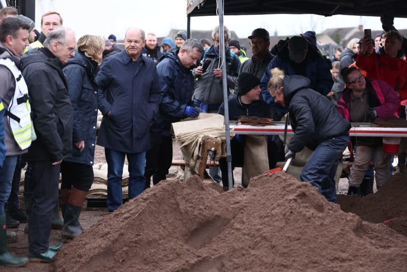 German Chancellor Olaf Scholz (C), Steffi Lemke (4-L), German Minister for the Environment, Nature Conservation, Nuclear Safety and Consumer Protection, and Reiner Haseloff (2-L), Minister President of Saxony-Anhalt, during a visit to the central sandbag filling facility in Berga. On the same day, Chancellor Scholz and Saxony-Anhalt's Minister President Haseloff will visit the flood area around the Helme and talk to volunteers. Jan Woitas/dpa