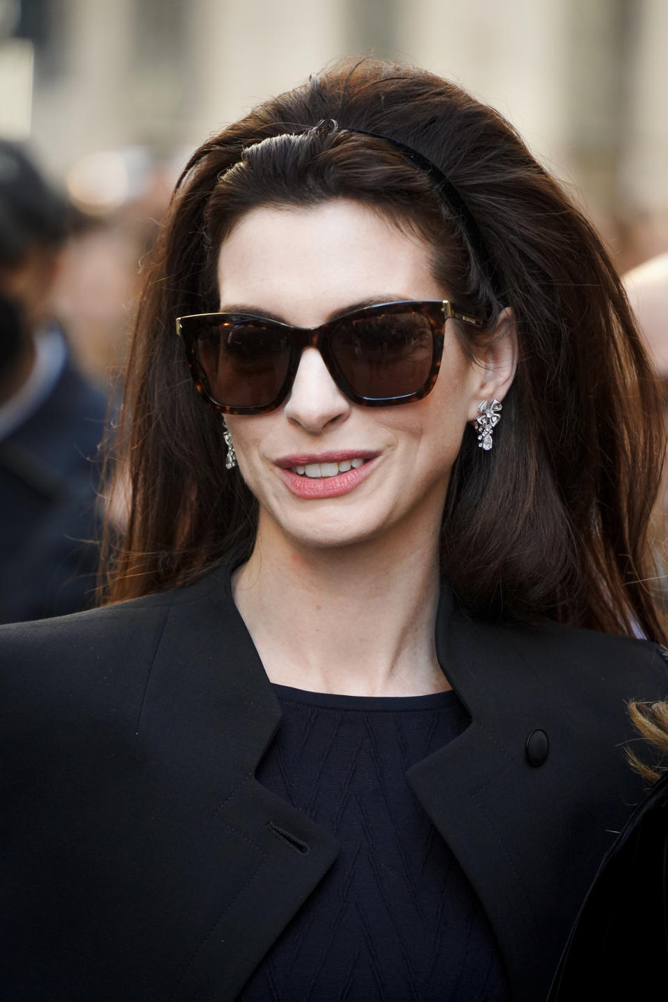 Anne Hathaway wearing sunglasses and looking down