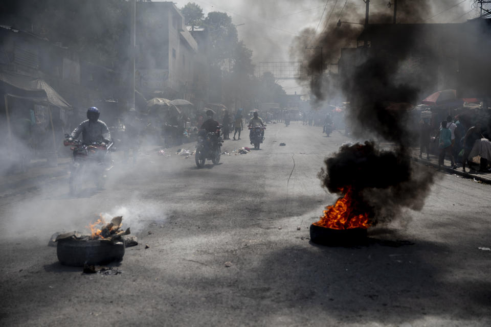 Motorcycles ride past a barricade of burning tires during a protest by residents over a police raid that resulted in the death of a young musician, in downtown Port-au-Prince, Haiti, Wednesday, Sept. 22, 2021. Violence can breakout at any time, in any random corner of the city. Angry mobs gather and dissolve, reunite and prepare for a new confrontation, while bystanders await the unexpected. (AP Photo/Rodrigo Abd)