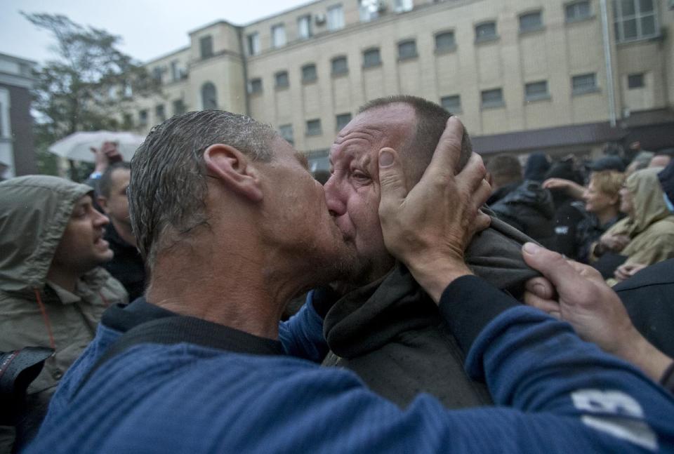 A man gets a kiss from a supporter, left, after being released from a local police station which was stormed by pro-Russian protesters in Odessa, Ukraine, Sunday, May 4, 2014. Several prisoners that were detained during clashes that erupted Friday between pro-Russians and government supporters in the key port on the Black Sea coast were released under the pressure of protesters that broke into a local police station and received a hero's welcome by crowds. (AP Photo/Vadim Ghirda)