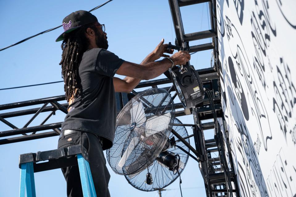 Paul Herring, 29, of Flint, installs lighting and fans for a designated cannabis space at the Soaring Eagle Arts Beats & Eats festival in Royal Oak on Thursday, Aug. 31, 2023.